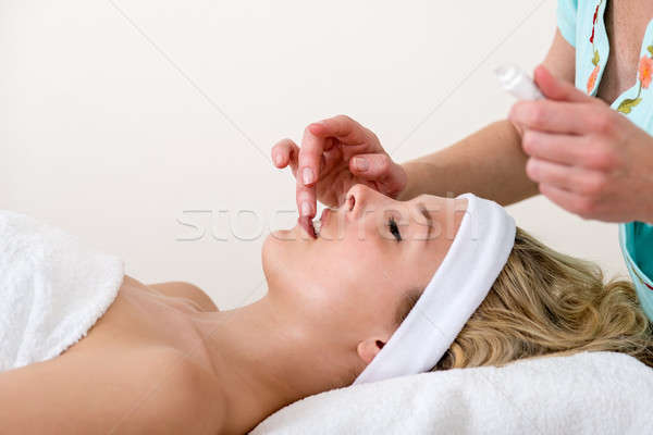Beautician applying balm on the lips of a woman.  Stock photo © belahoche