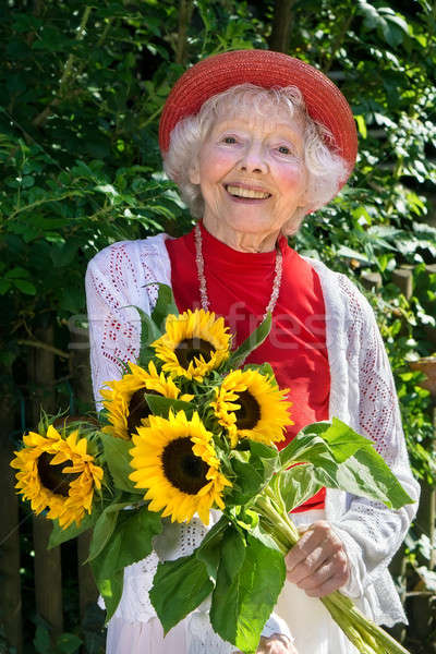 Friendly senior lady with a bunch of sunflowers.  Stock photo © belahoche
