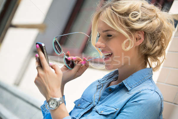 Cute blonde talking on a cell phone. Stock photo © bezikus