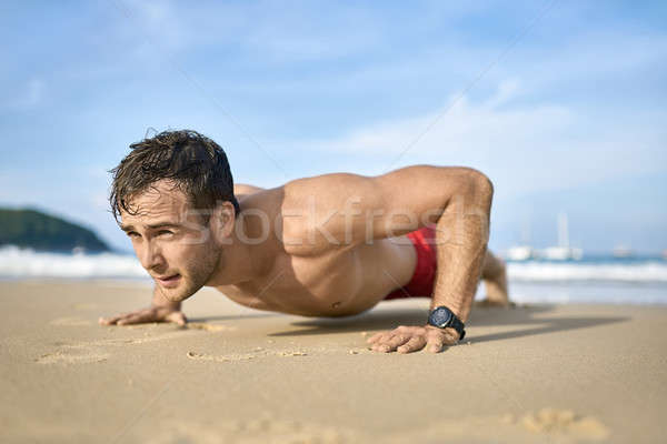 Sportive guy training on beach Stock photo © bezikus