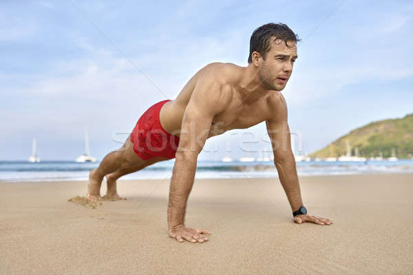 Athletic guy training on beach. Daylight shooting. Stock photo © bezikus