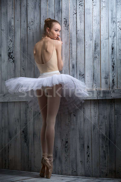 Stock photo: Modest ballerina standing near a wooden wall