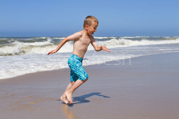 Boy fleeing a wave at sandy beach Stock photo © bigandt
