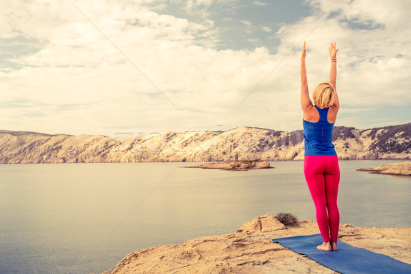 Woman meditating in yoga tree pose at the sea and mountains Stock photo © blasbike