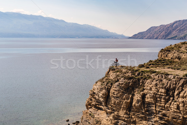 Stock photo: Mountain biker riding bike on rocks at the ocean