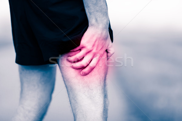 Stock photo: Leg pain, man holding sore and painful muscle