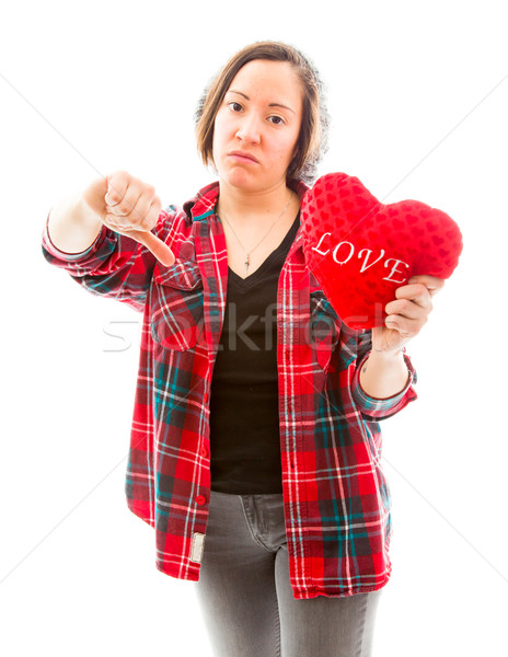 Stock photo: Young woman holding heart shape and showing thumbs down sign
