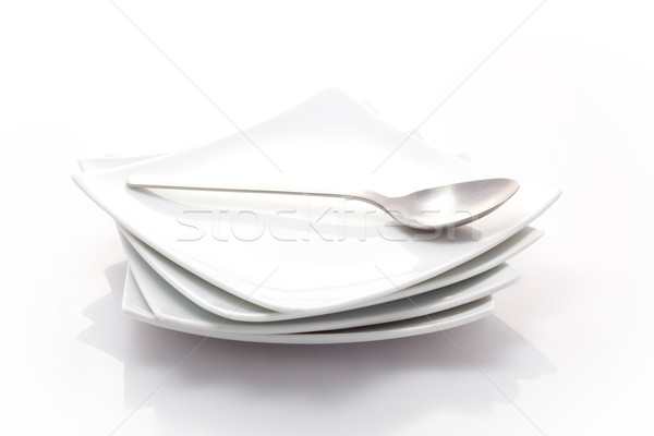 Stock photo: stack of square plates with a spoon isolated on a white backgrou