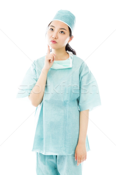 Asian female surgeon looking up with finger on chin isolated on white background Stock photo © bmonteny