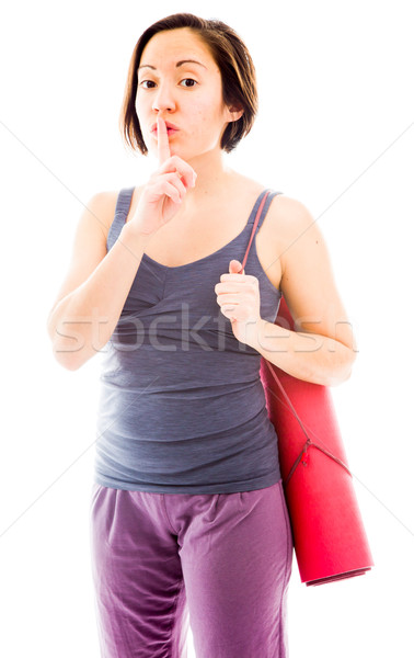 Young woman carrying exercise mat with a finger on lips Stock photo © bmonteny
