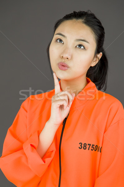 Young Asian woman with finger on chin in prisoners uniform Stock photo © bmonteny