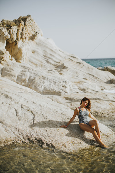 Pretty yung woman on the stony seaside beach Stock photo © boggy