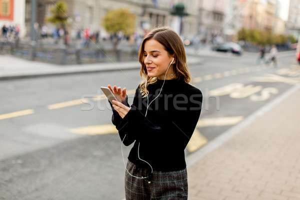Young brunette woman using mobile while standing on street and   Stock photo © boggy