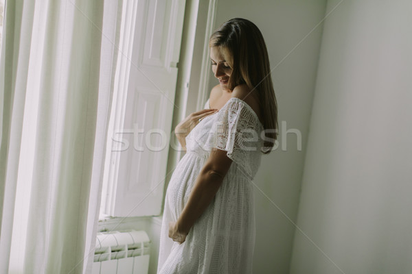 Young pregnant woman standing by the window Stock photo © boggy