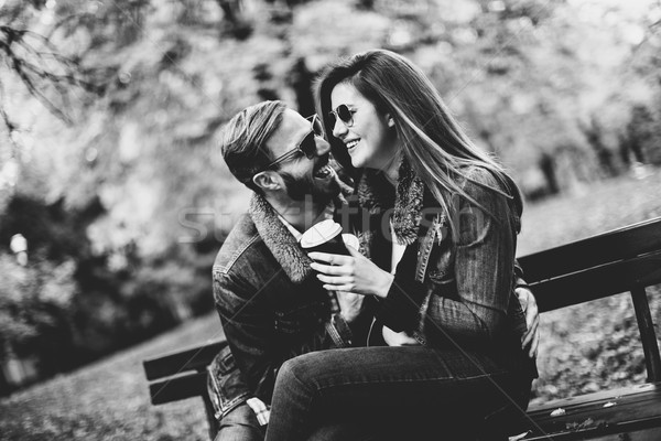 Young loving couple on a bench in autumn park and holding coffee Stock photo © boggy