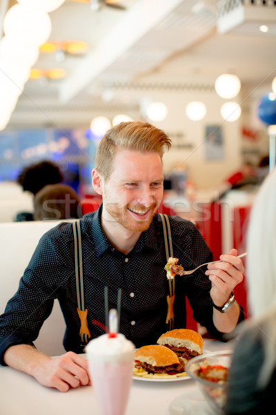 Young man eating cheeseburger in diner Stock photo © boggy