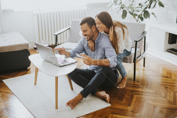 Cheerful couple searching internet on laptop at home Stock photo © boggy