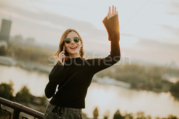 Young woman holding mobile phone while standing on walkway by th Stock photo © boggy