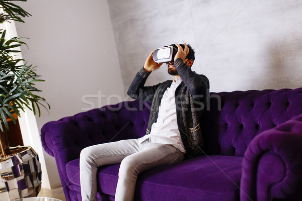 Bearded young man wearing virtual reality goggles in modern room Stock photo © boggy