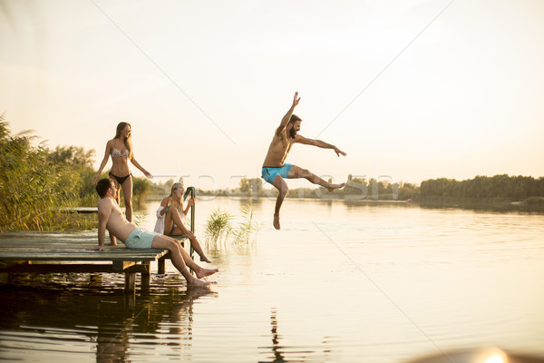 Group of young people having fun on pier at the lake Stock photo © boggy