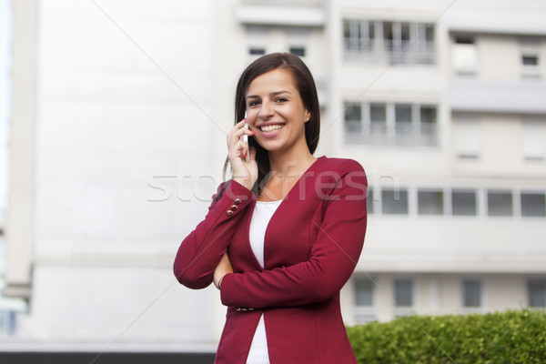 Young businesswoman in red blazer talking over the mobile phone Stock photo © boggy
