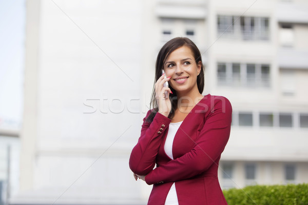Young businesswoman in red blazer talking over the mobile phone Stock photo © boggy
