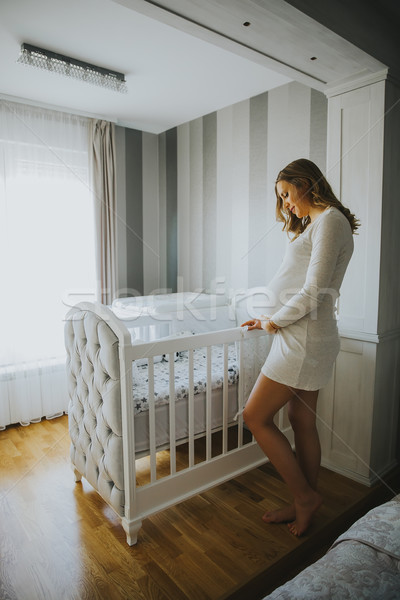 Pregnant woman setting up baby crib and smiling Stock photo © boggy