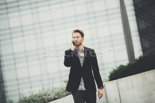 Young businessman with mobile phone on the street Stock photo © boggy