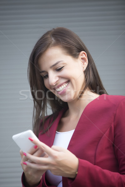 Young businesswoman in red blazer using mobile phone outdoor Stock photo © boggy