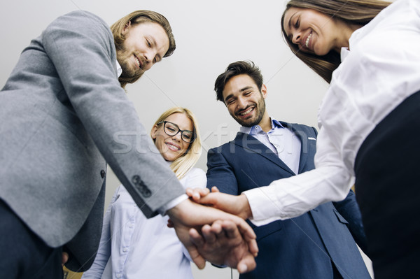 Young coworkers putting hands together as symbol of unity in the Stock photo © boggy