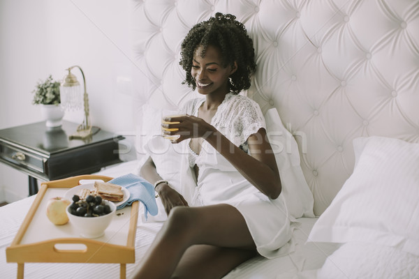 Smiling african american woman having a relaxing breakfast in be Stock photo © boggy