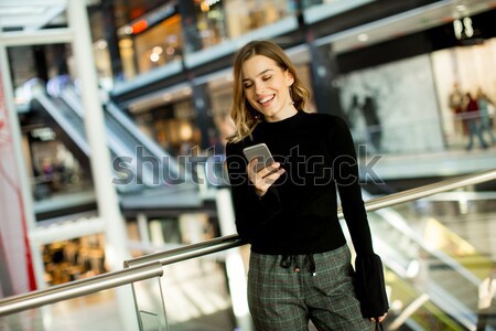 Fiatal nő néz mobiltelefon vásárlás központ portré Stock fotó © boggy