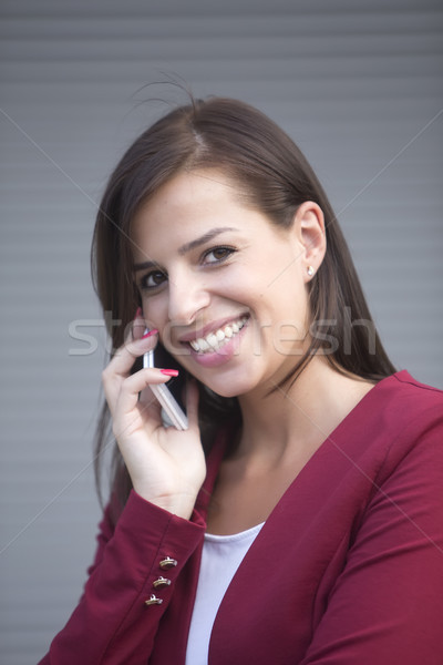 Fiatal üzletasszony piros blézer beszél mobiltelefon Stock fotó © boggy