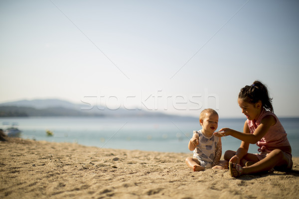 Cute little sisters sitting on a beach Stock photo © boggy