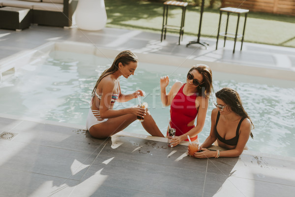 Young women drinking coctail and having fun by swimming pool Stock photo © boggy