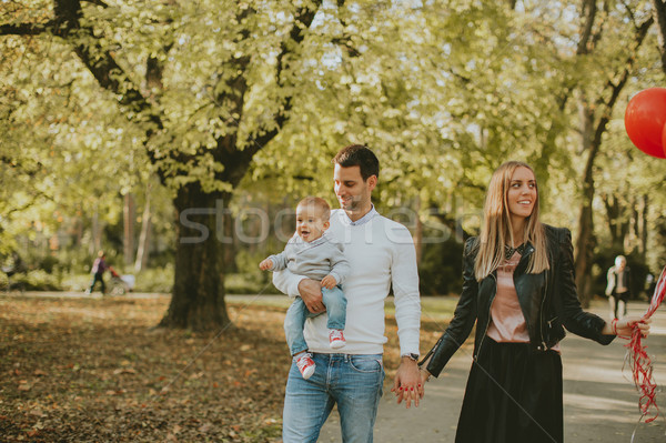 Happy young parents with baby boy in autumn park holding red bal Stock photo © boggy