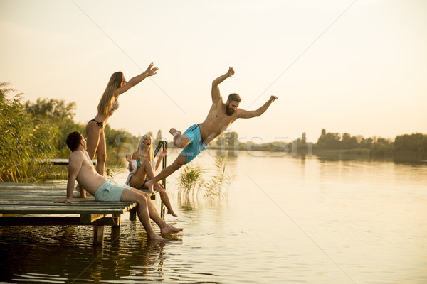 Group of young people having fun on pier at the lake Stock photo © boggy
