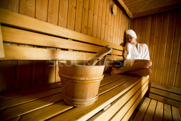 Young woman wrapped in a white towel relaxing in wooden sauna ro Stock photo © boggy
