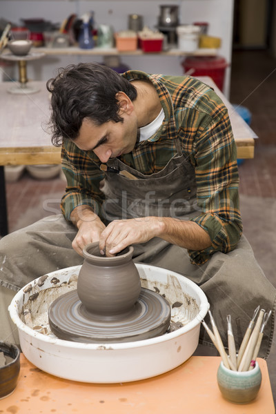 Artist makes clay pottery on a spin wheel in workshop Stock photo © boggy
