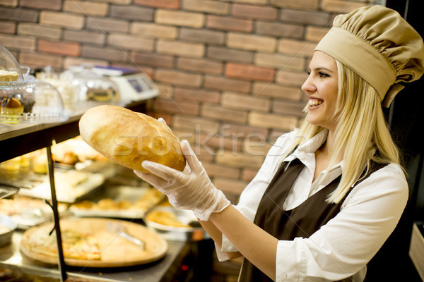 Young woman takes fresh bread from the shelves in a baker shop Stock photo © boggy