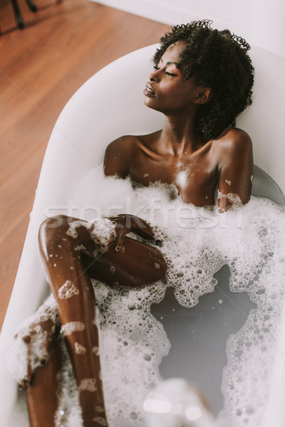 Stock photo: Young afro american young woman laying in bath with foam