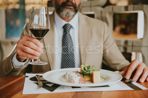 Handsome bearded businessman having lunch and drinking red wine  Stock photo © boggy