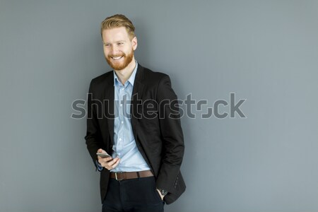 Redhair man using mobile phone standing by the wall Stock photo © boggy