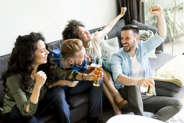Friends watching TV , drinking cider and having fun in the room Stock photo © boggy