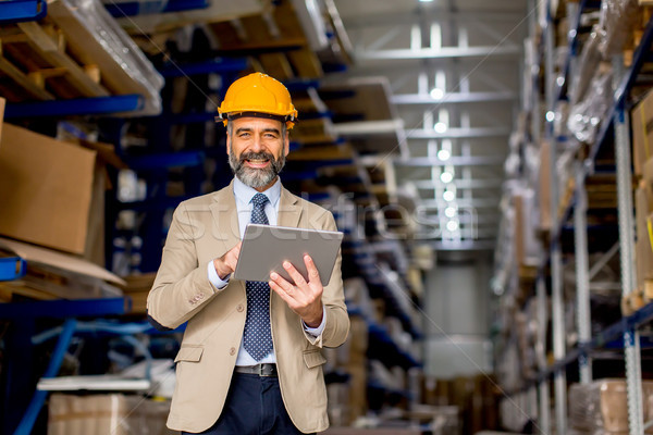 Mature engineer in the warehouse with digital tablet Stock photo © boggy