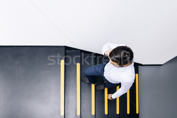 Young businessman talking on mobile phone and climbing on the st Stock photo © boggy