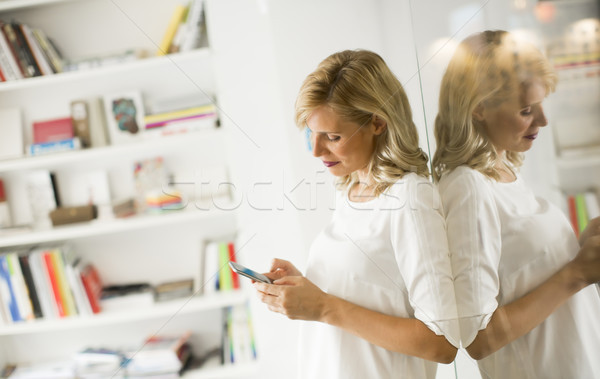 Confident blonde business woman standing and using phone in an o Stock photo © boggy