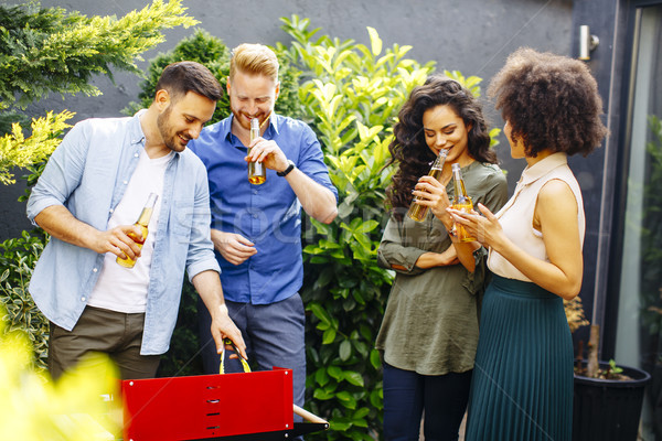 Happy friends grilling food and enjoying barbecue party outdoors Stock photo © boggy