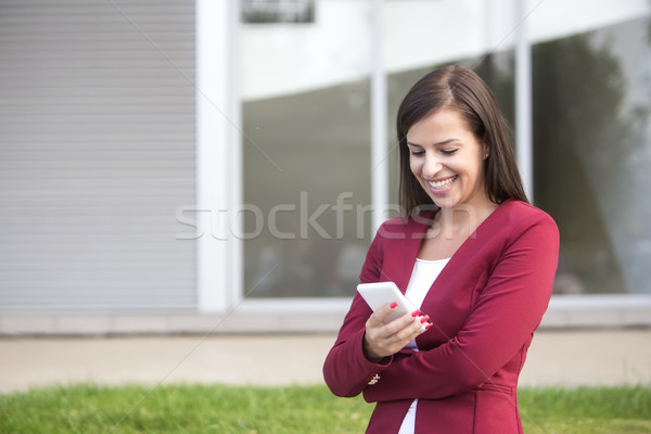 Young businesswoman in red blazer using mobile phone outdoor Stock photo © boggy