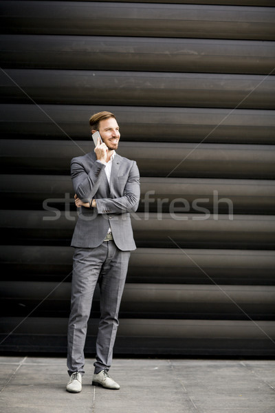 Handsome businessman with mobile phone by office building Stock photo © boggy